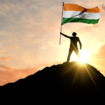 A man on the top of a mountain waving a India flag