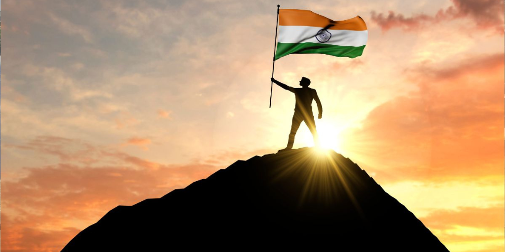 A man on the top of a mountain waving a India flag